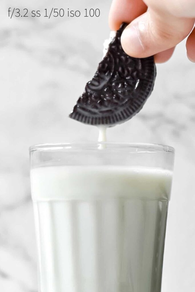 an oreo cookie being dipped into milk