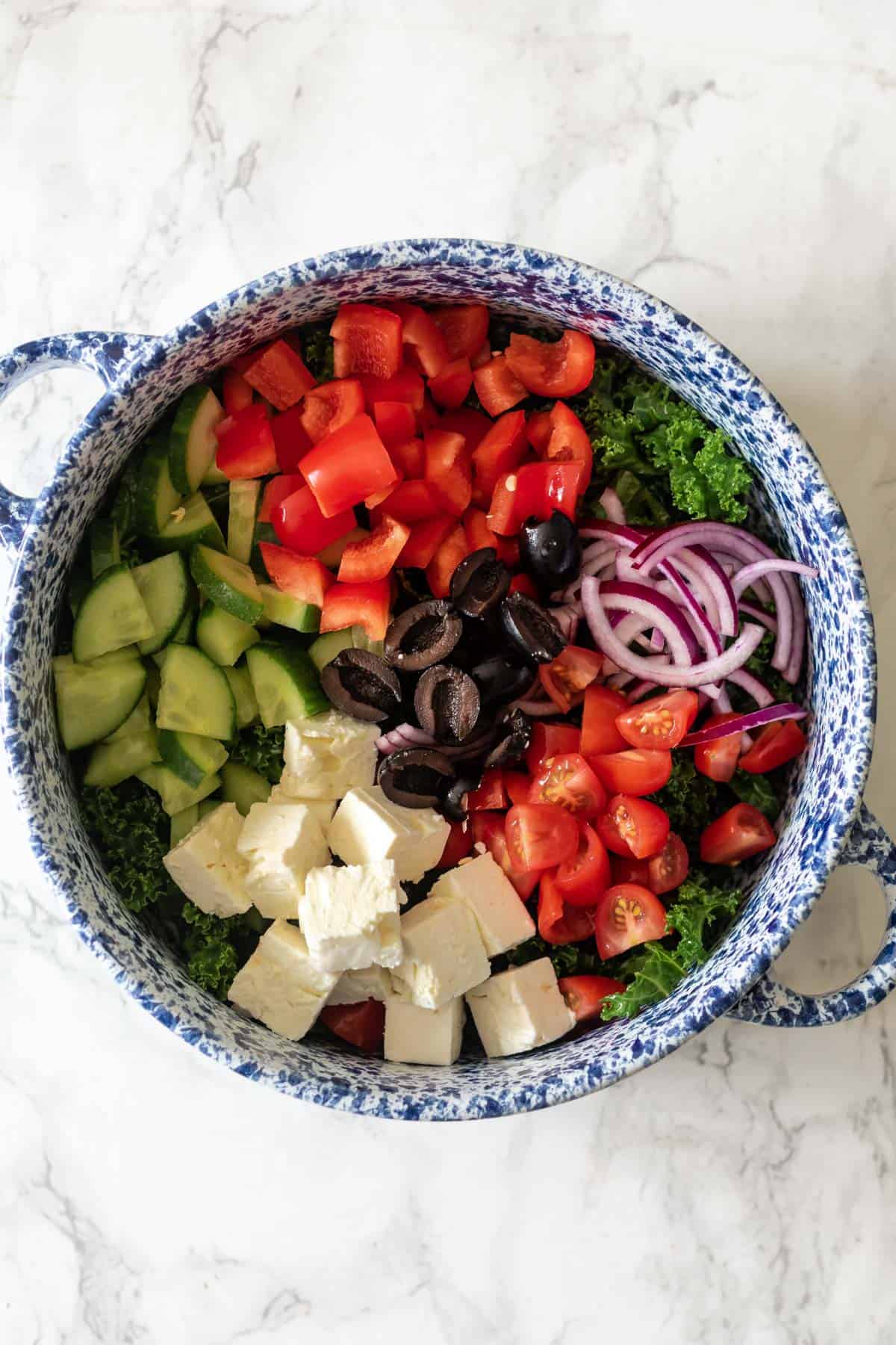 a bowl of kale greek salad showing all the ingredients required