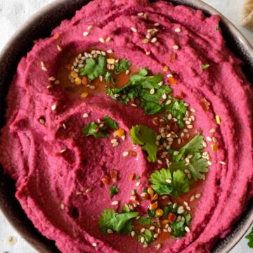 pink hummus topped with coriander and sesame seeds