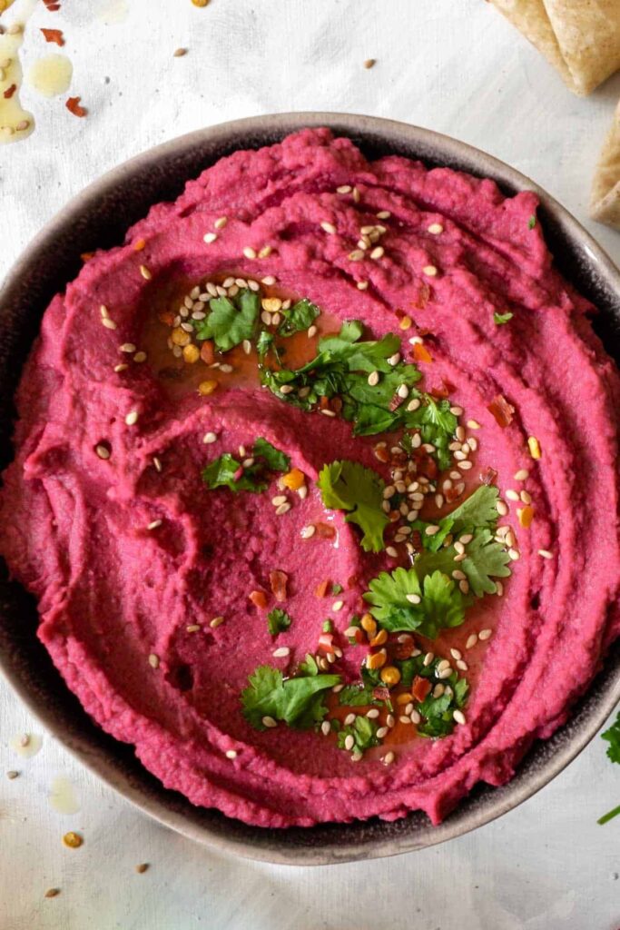 pink hummus topped with coriander and sesame seeds