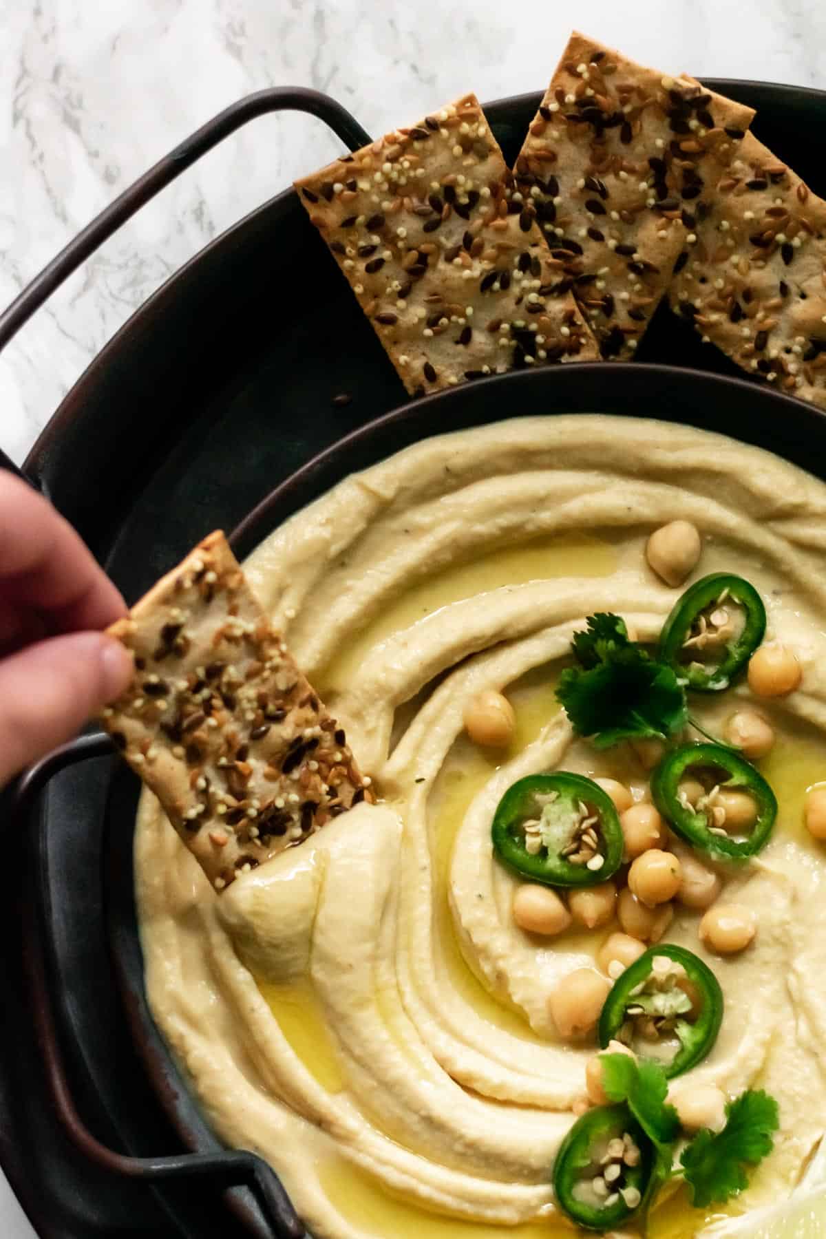 a cracker being dipped into hummus