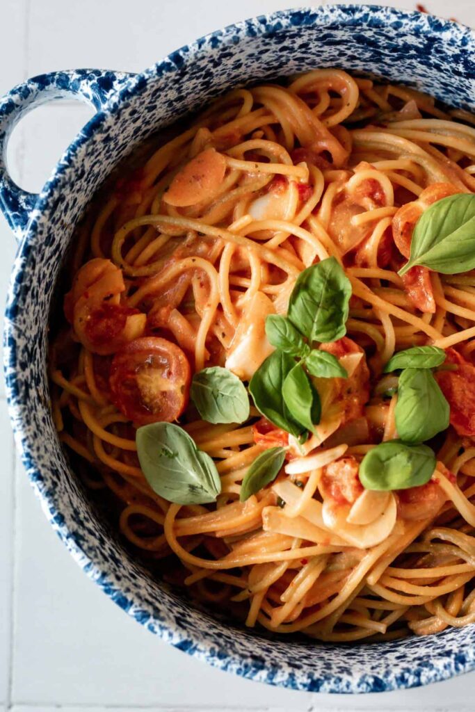 a pot of tomato spaghetti topped with basil