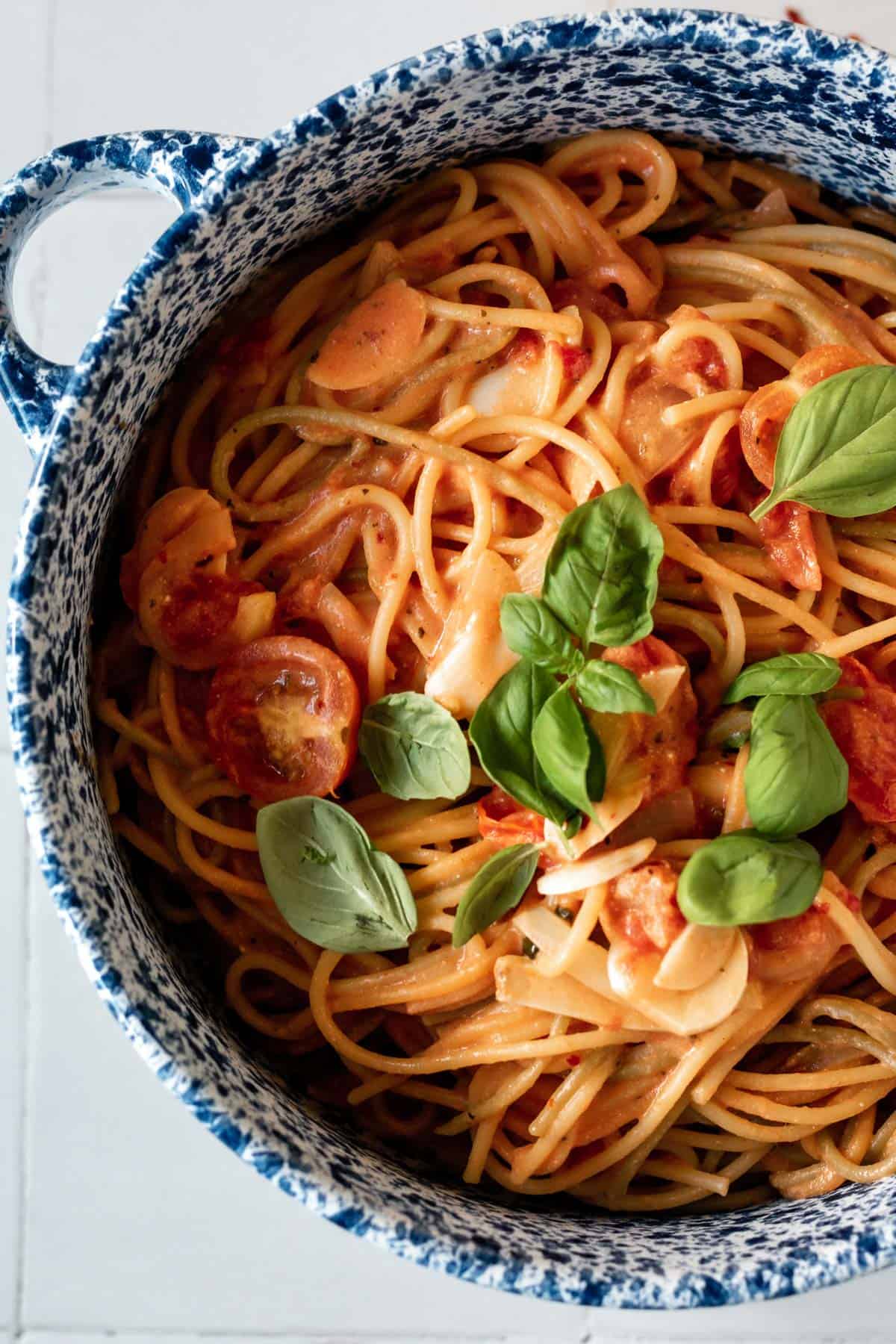 a pot of tomato spaghetti topped with basil