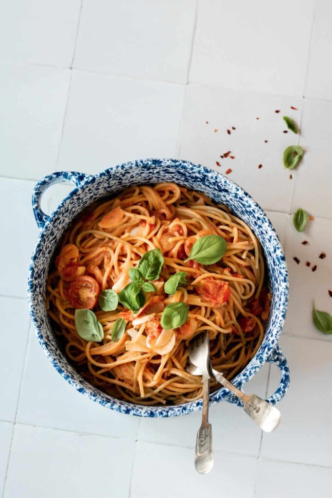 a bowl of spaghetti topped with basil