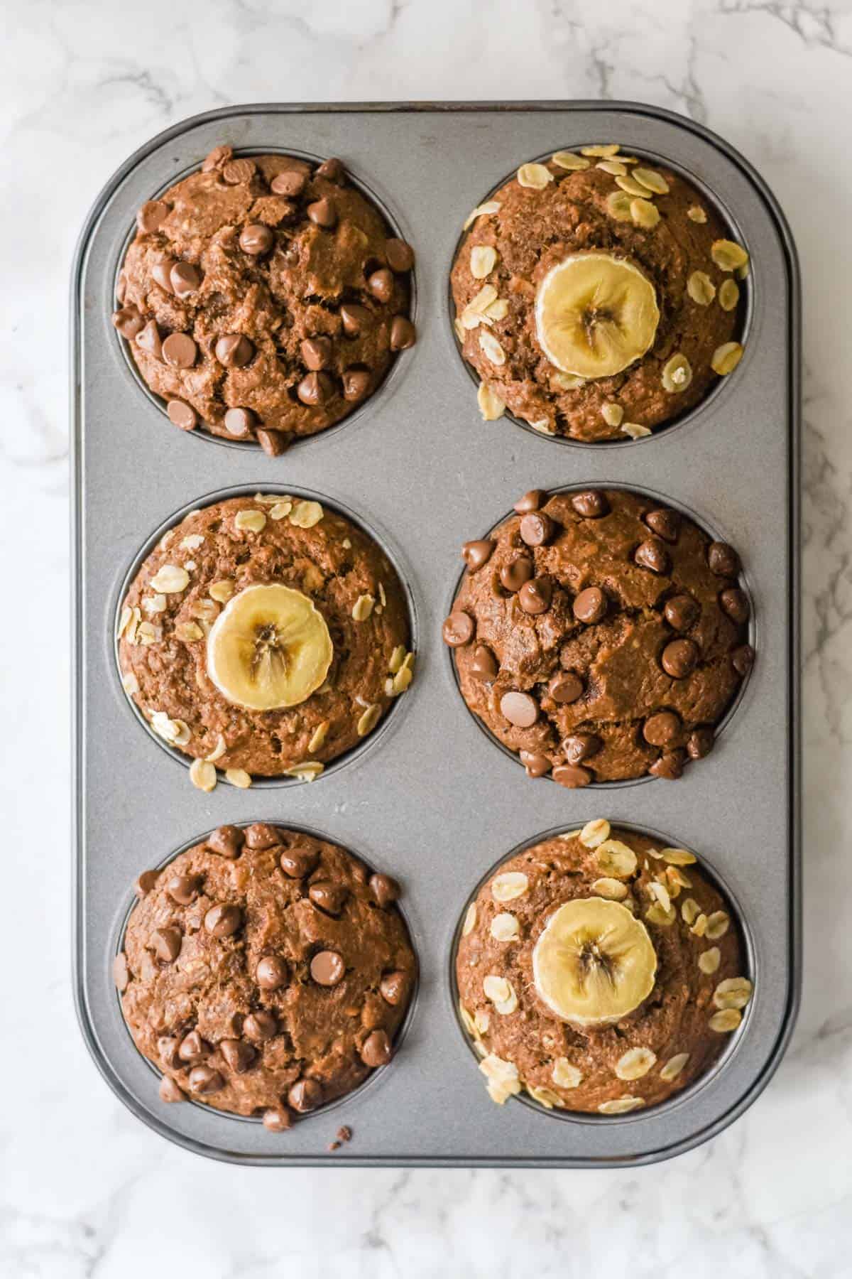 six baked muffins topped with banana and chocolate chips