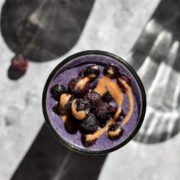 a glass of blueberry smoothie topped with almond butter