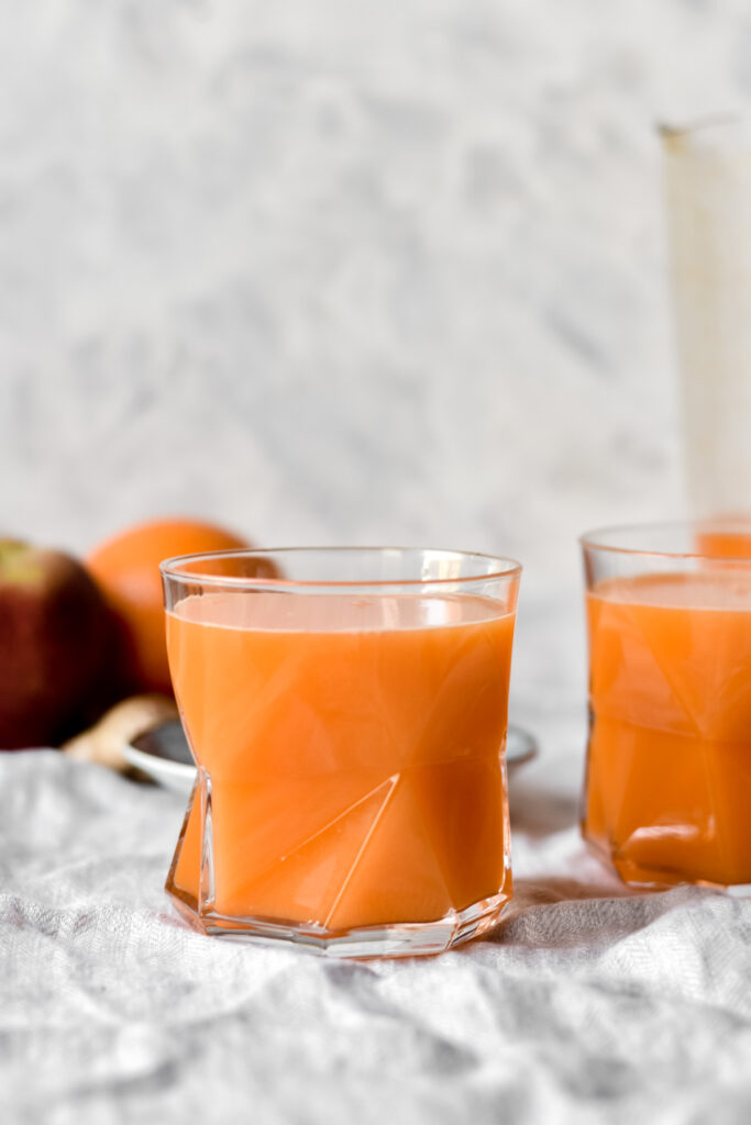 two glasses of freshly made carrot, orange and ginger juice