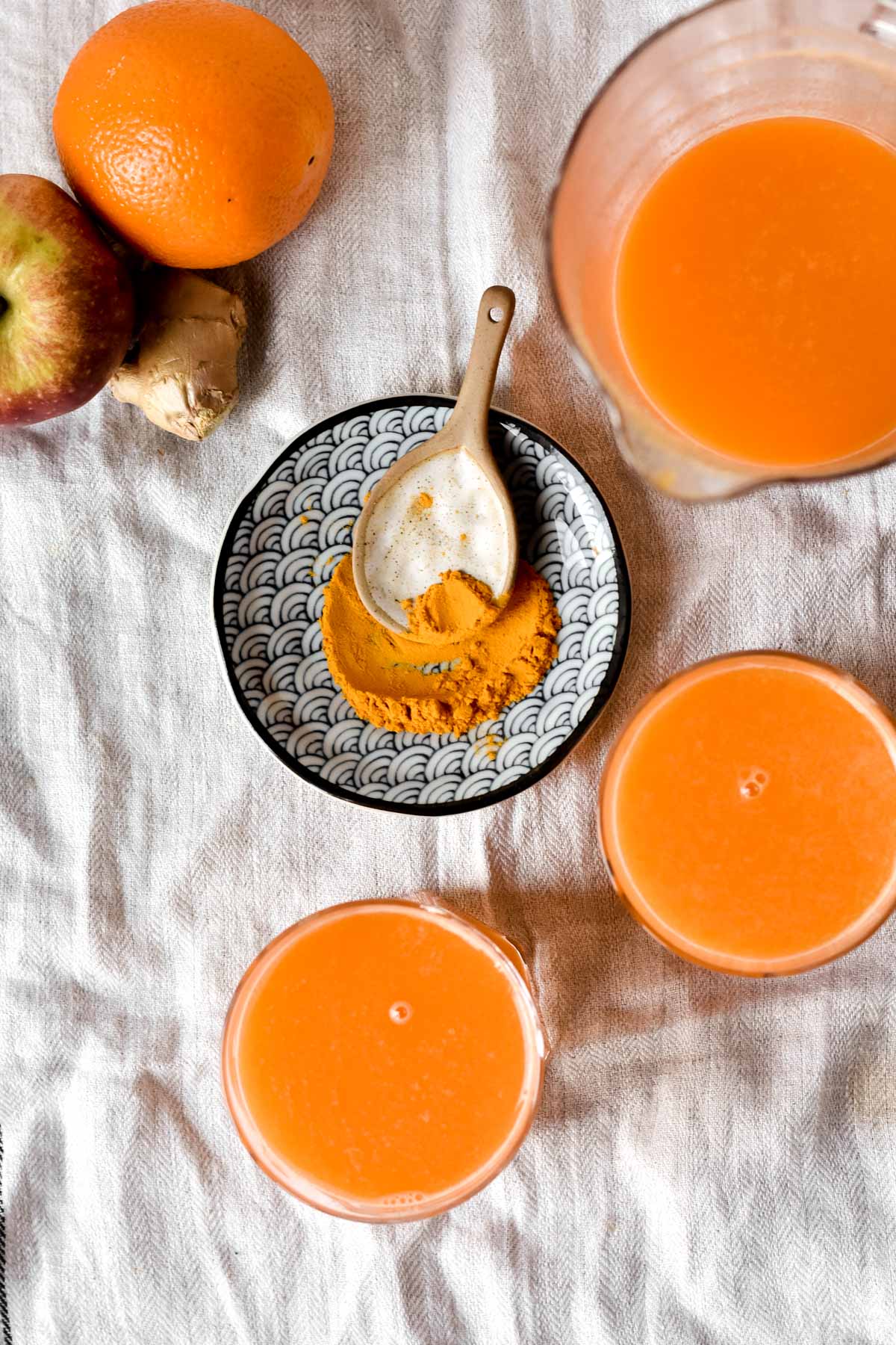 a jug of juice with some glasses and fruit