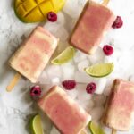 four popsicles arranged on ice with fruit