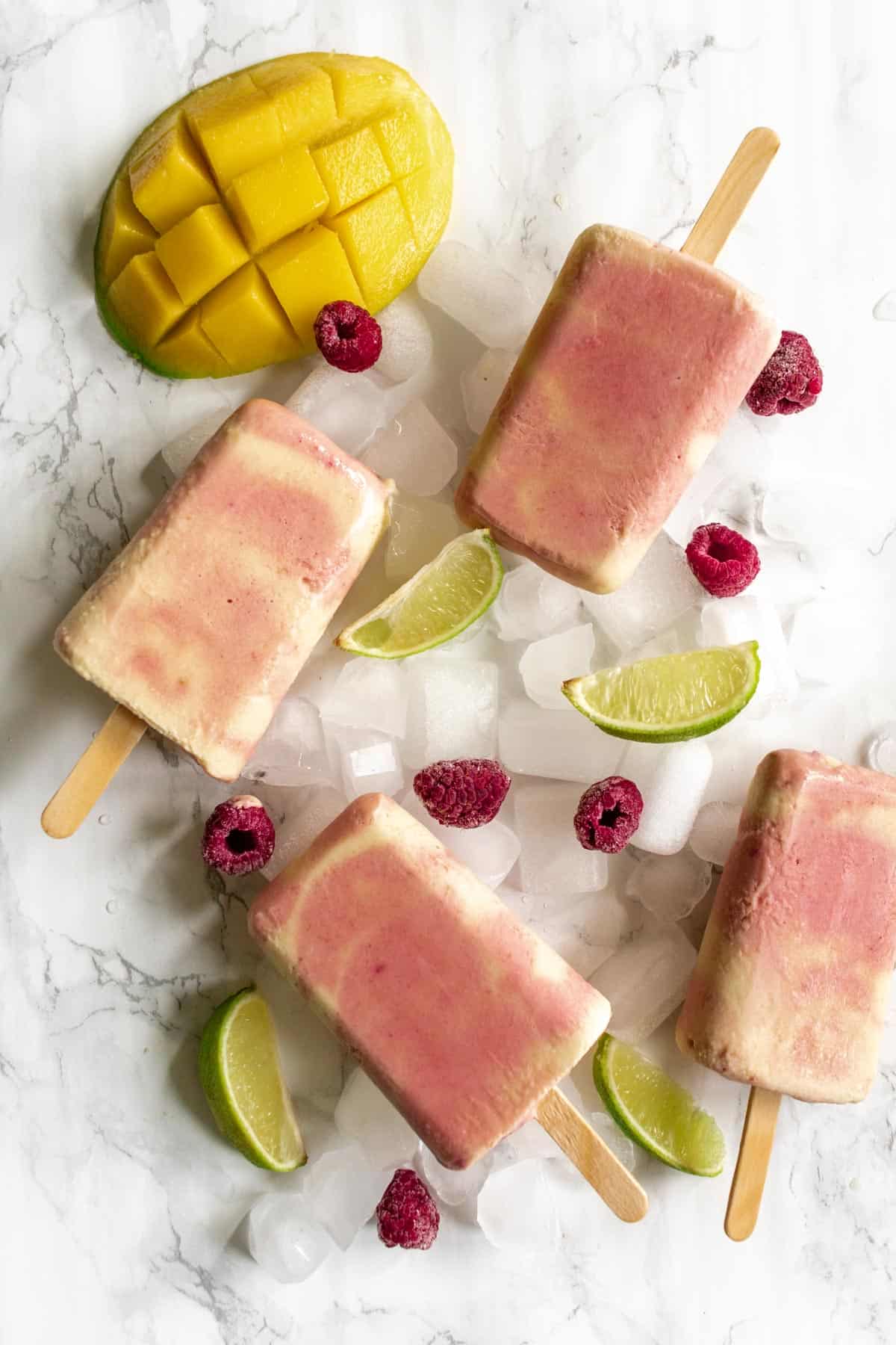 four popsicles arranged on ice with fruit