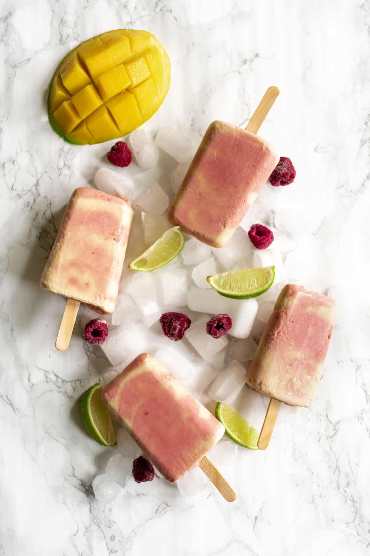 four popsicles on ice alongside lime wedges
