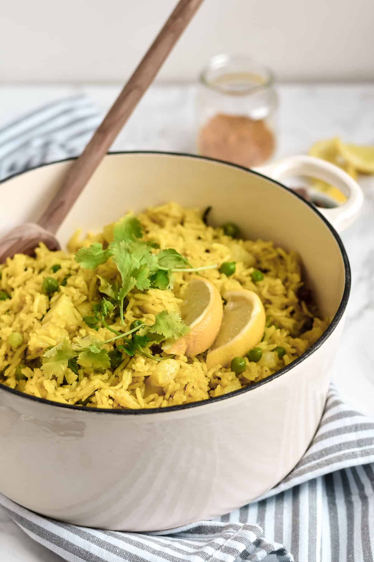 a pot of rice topped with lemon wedges and coriander