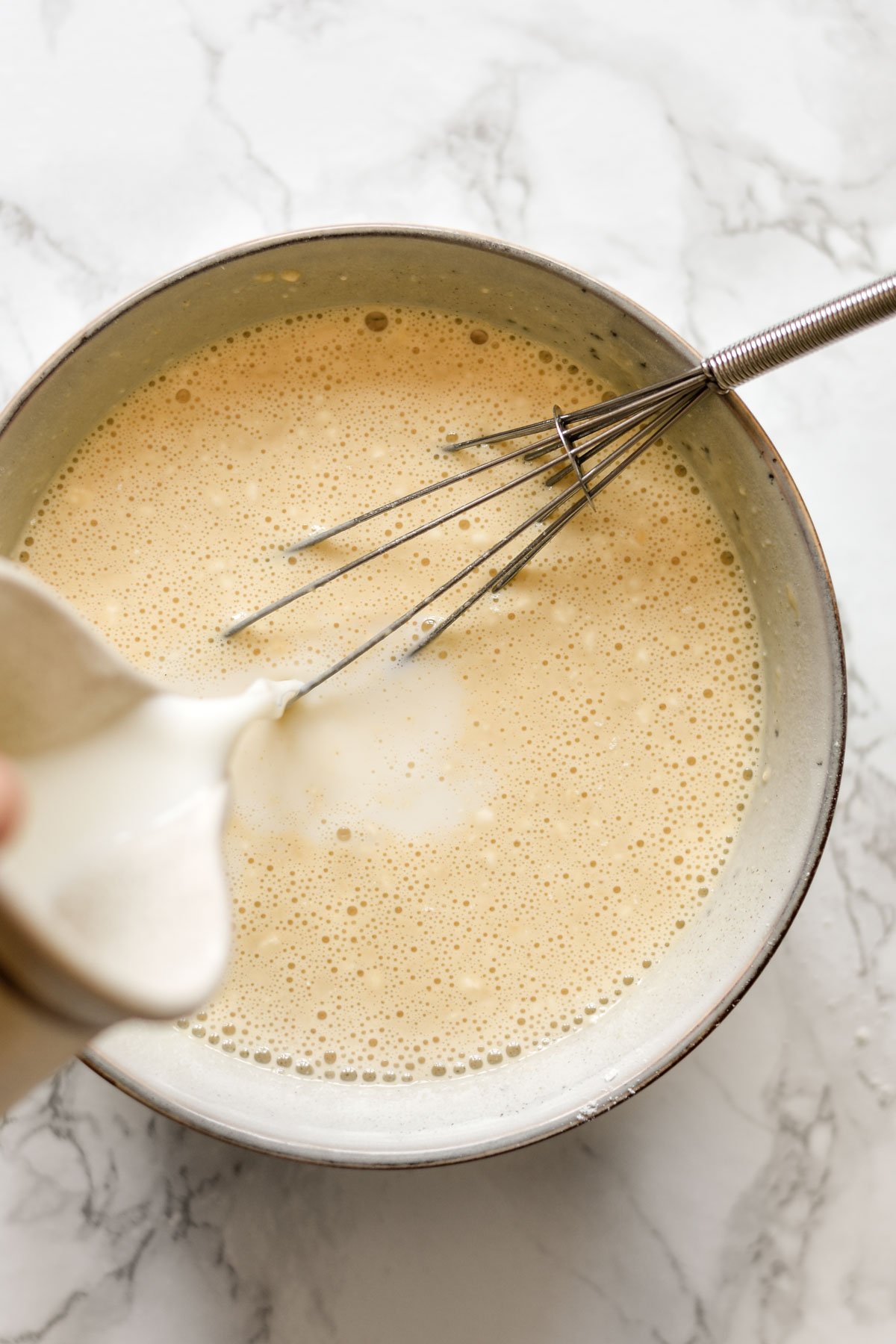 milk being poured into crepe batter