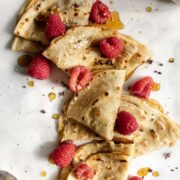 crepes topped with raspberries and maple syrup