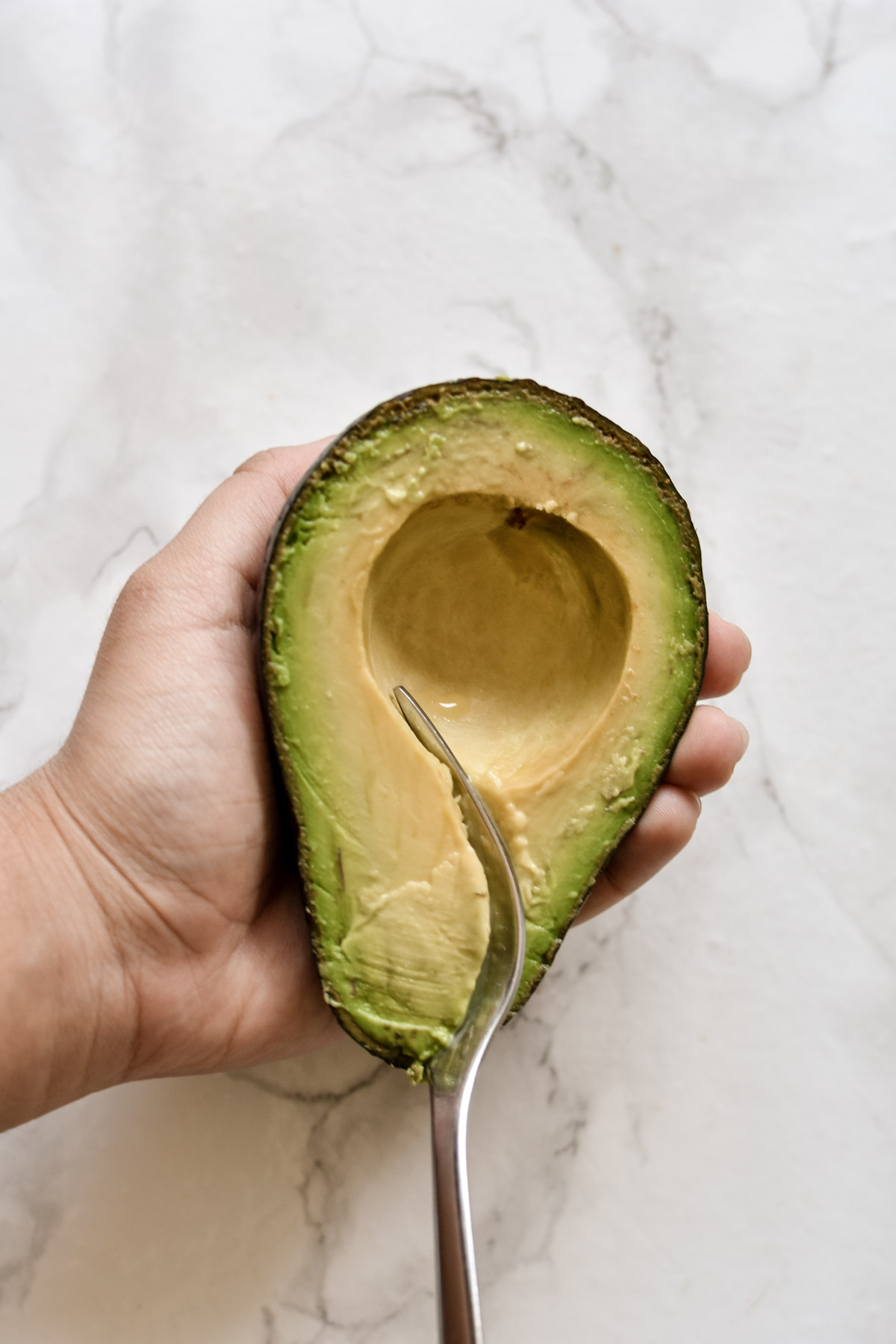 avocado flesh being scooped out with a fork