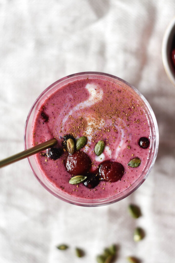 a glass of smoothie topped with berries
