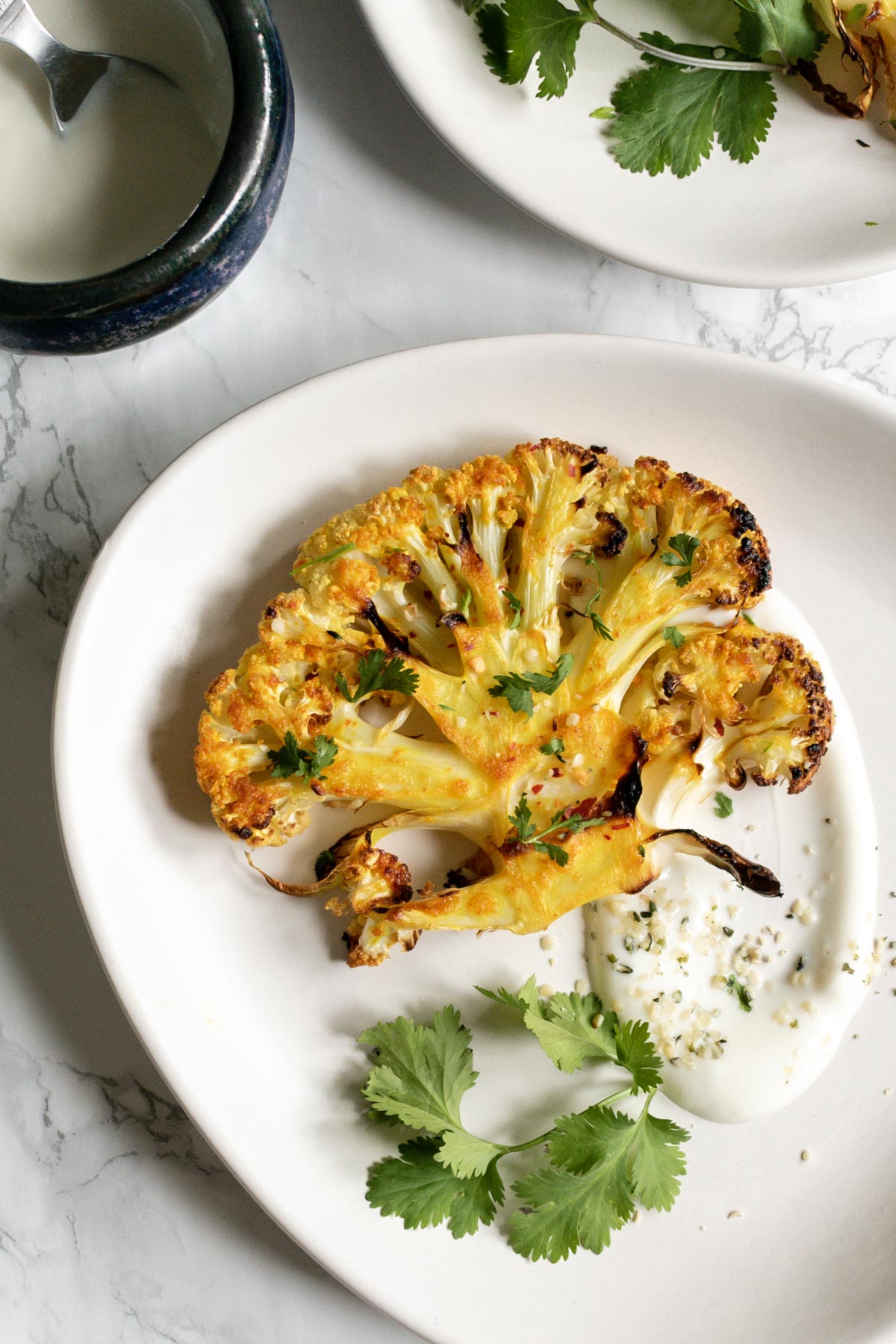 a cauliflower steak on a plate served with yoghurt