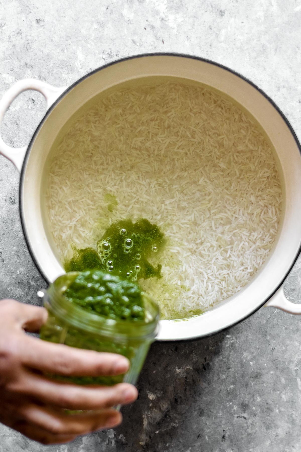 blended green sauce being poured into washed rice