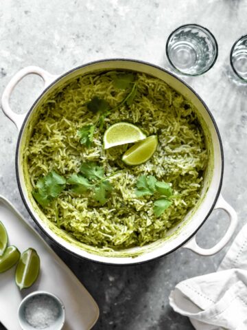 a large pot of green rice topped with lime wedges