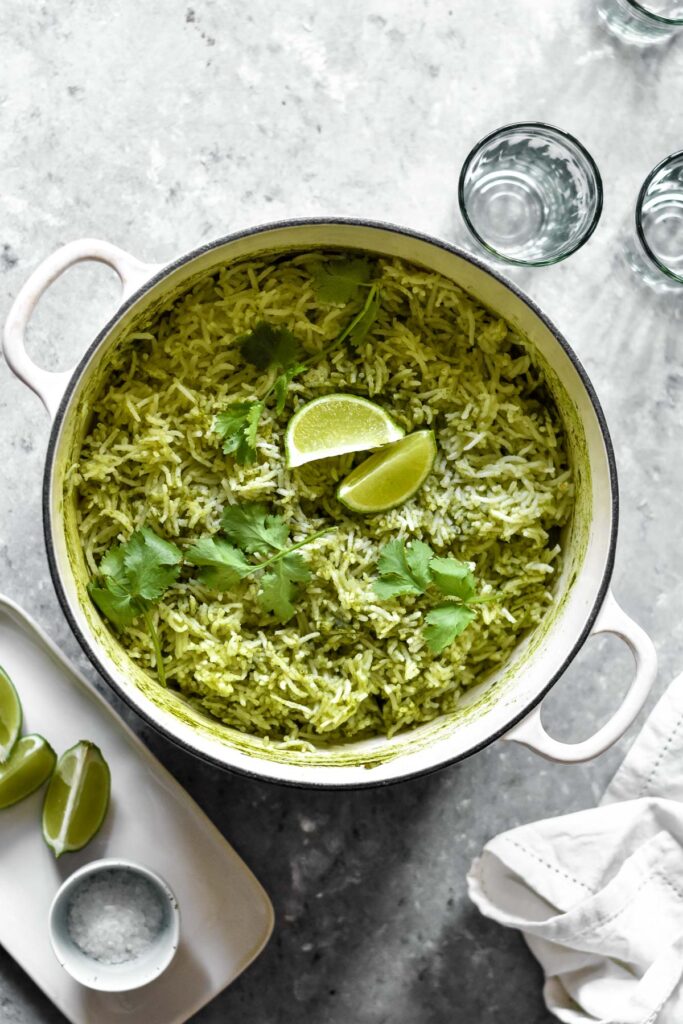 a large pot of green rice topped with lime wedges