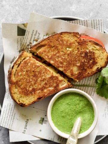 a bowl of chutney and two slices of grilled cheese