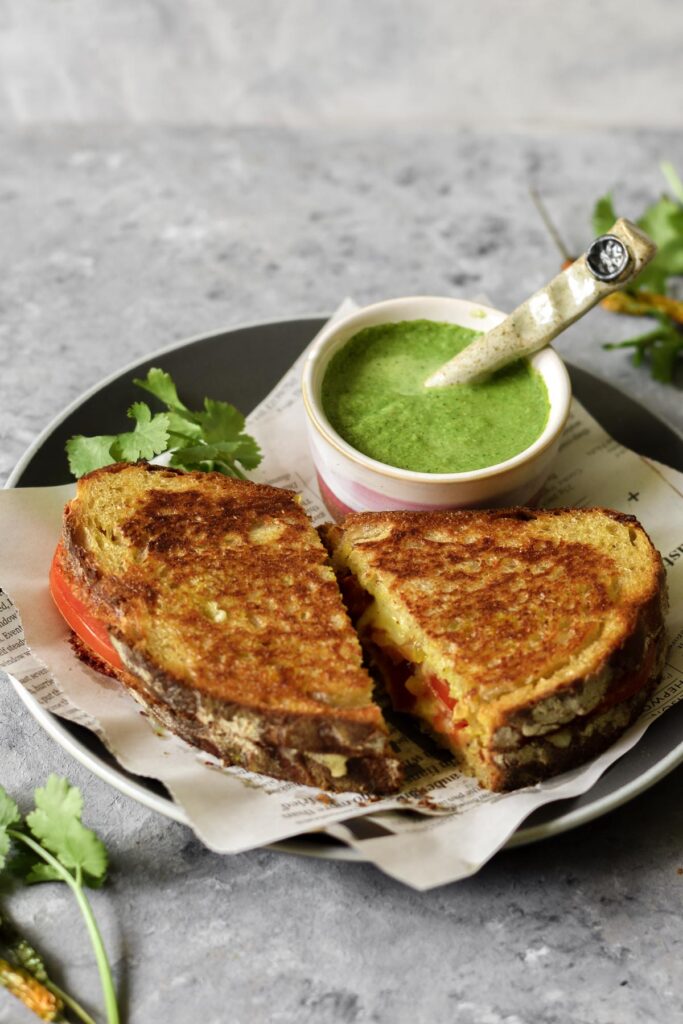 two slices of grilled cheese on a plate with a small bowl of chutney