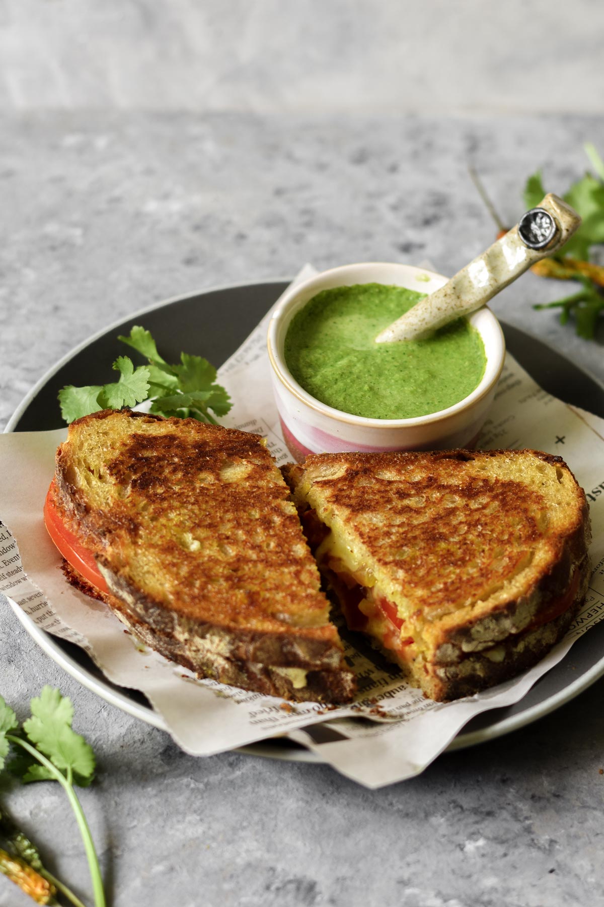 two slices of grilled cheese on a plate with a small bowl of chutney