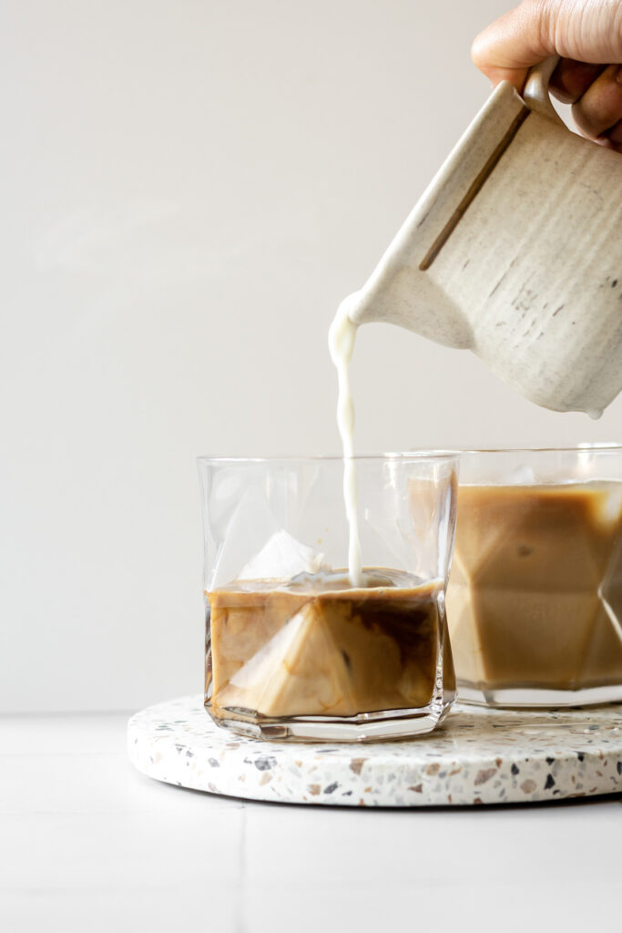 milk being poured into an iced latte