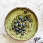 a green smoothie bowl topped with blueberries