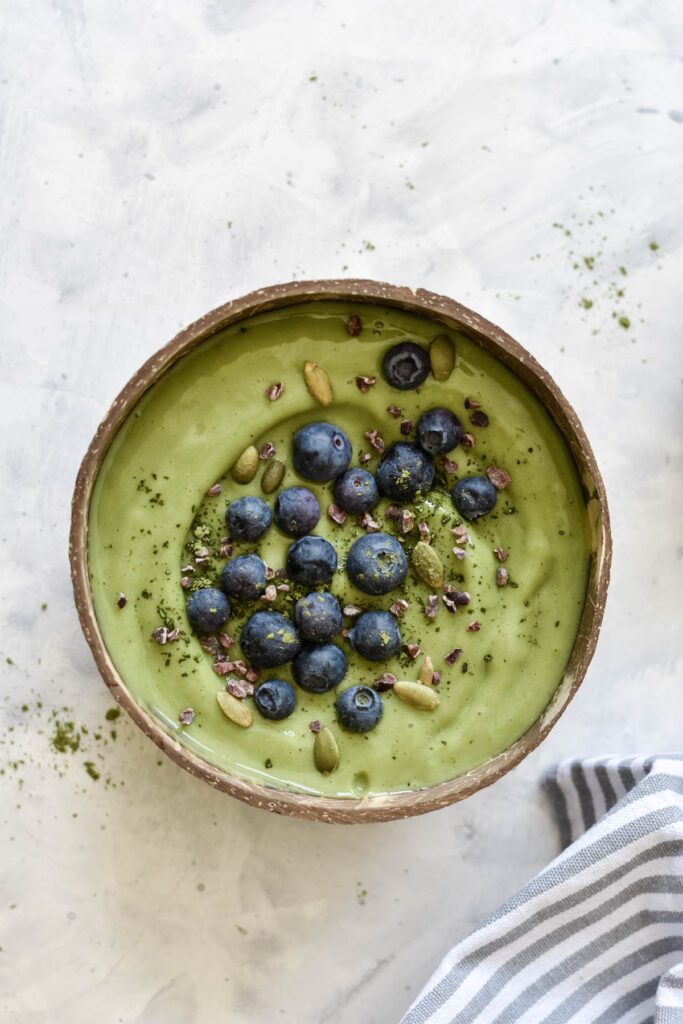 a green smoothie bowl topped with blueberries
