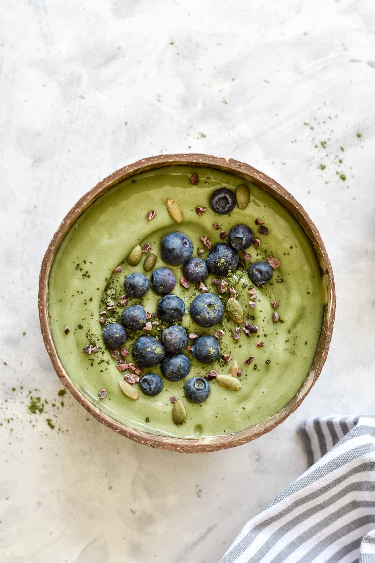 a green smoothie bowl topped with blueberries