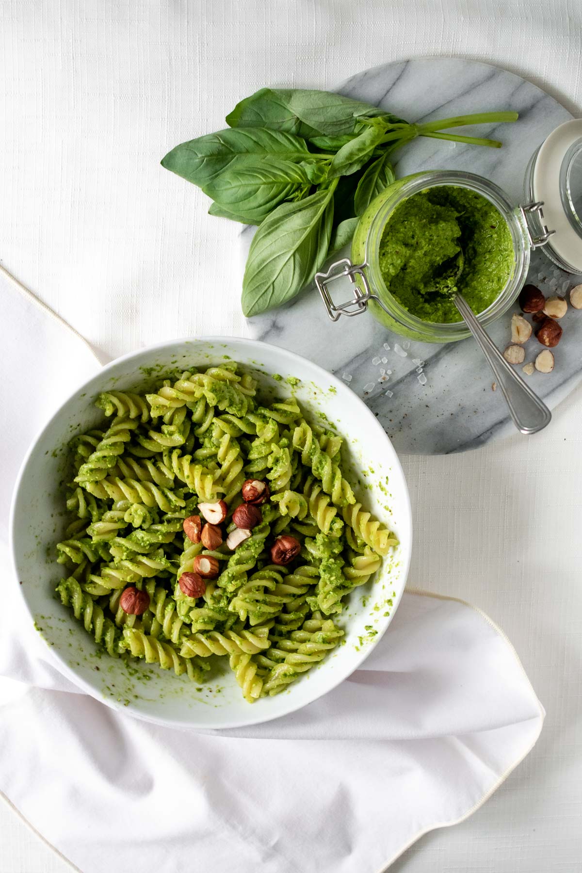 a bowl of pasta and a jar of vegan pesto