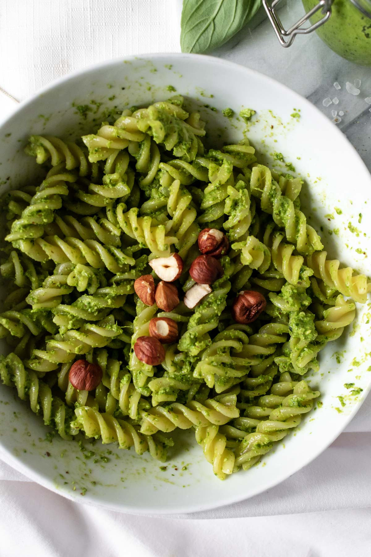 a bowl of pesto pasta topped with hazelnuts