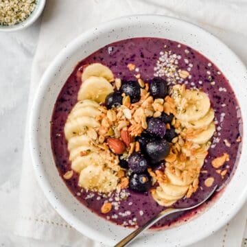 a blueberry smoothie bowl topped with granola and berries