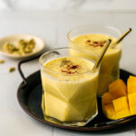 two glasses of mango lassi on a tray
