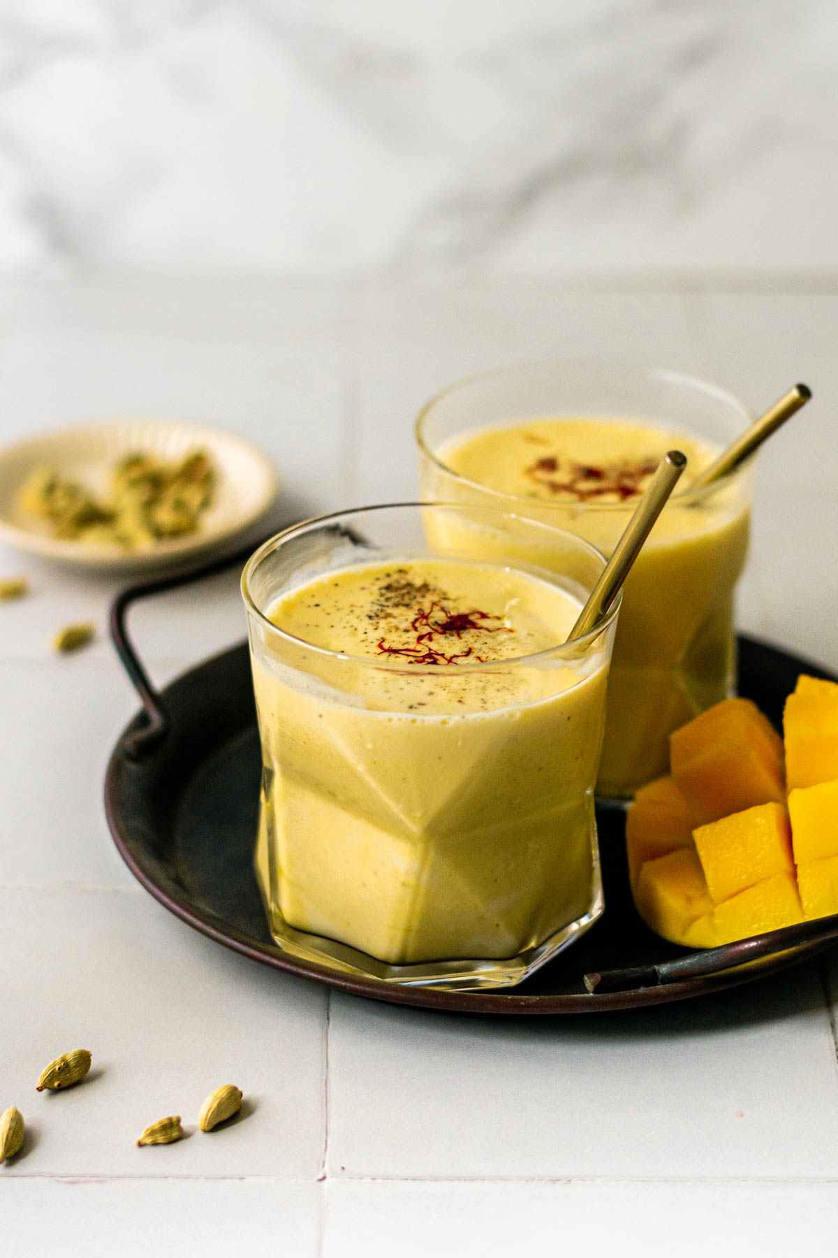 two glasses of mango lassi on a tray