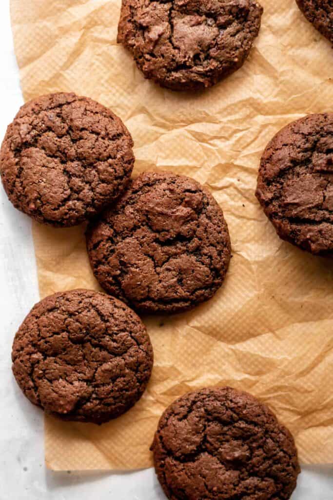some chocolate brownie cookies on a sheet of baking parchment