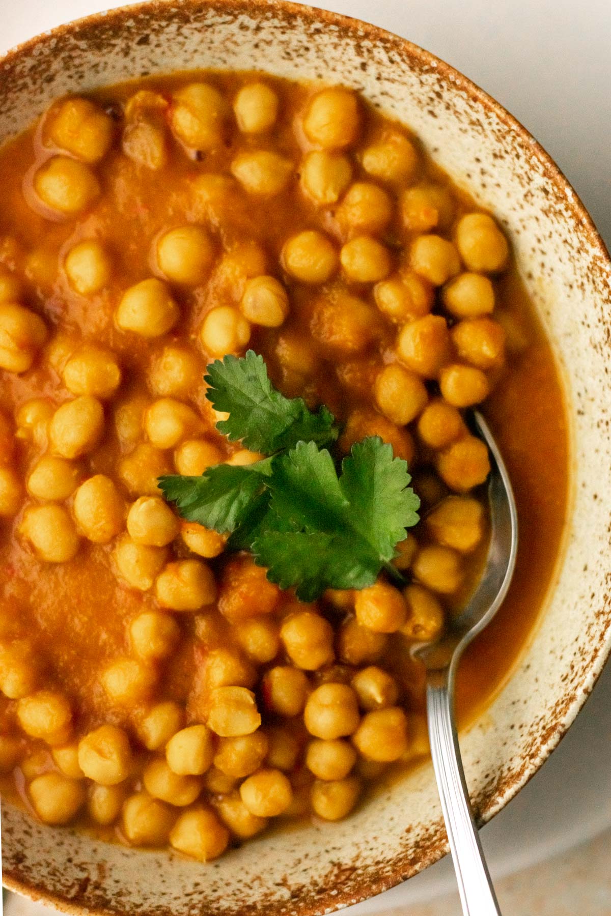 a bowl of chickpea curry topped with coriander leaves