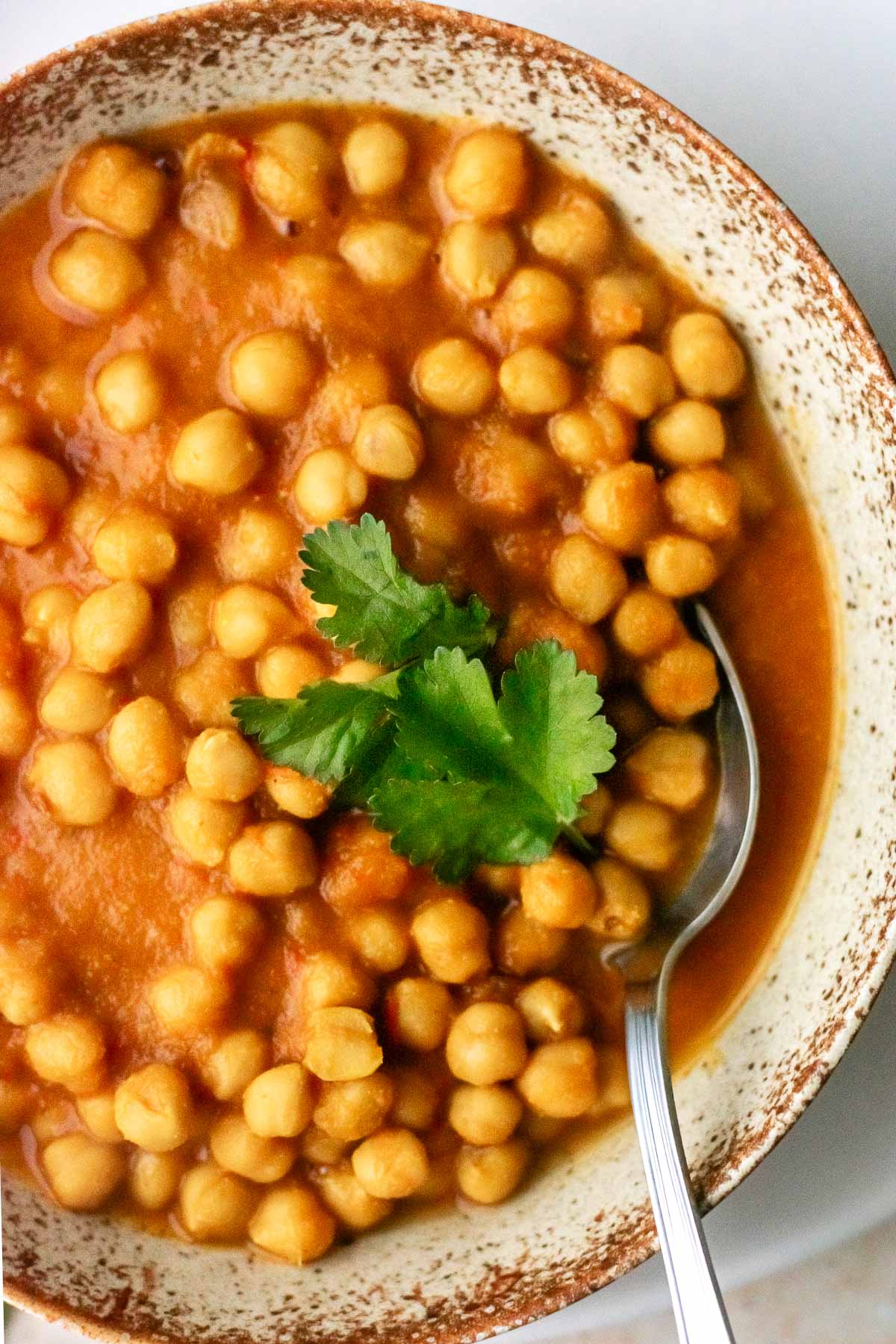 a bowl of chickpea curry topped with coriander leaves