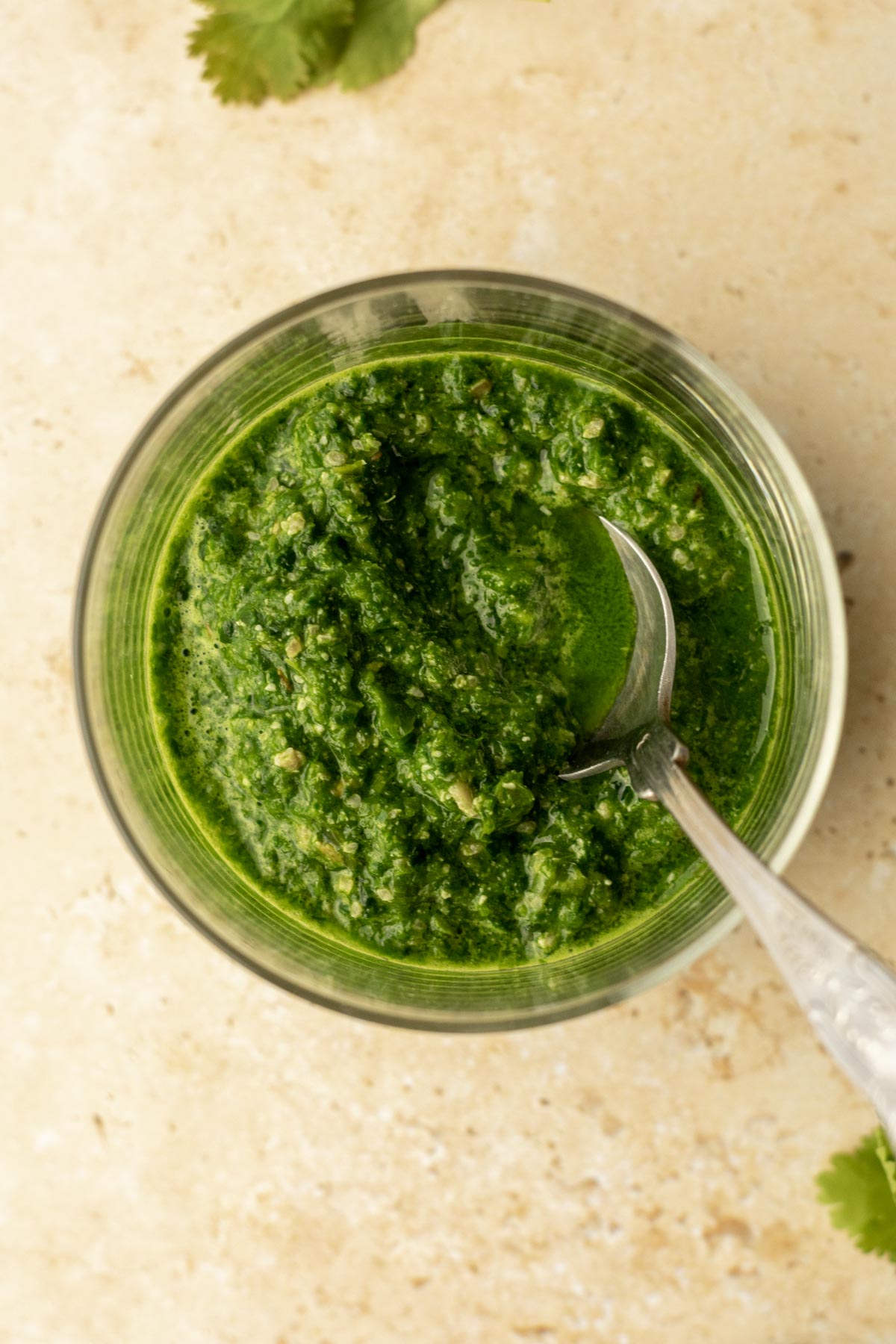 a bowl of green chutney with a spoon