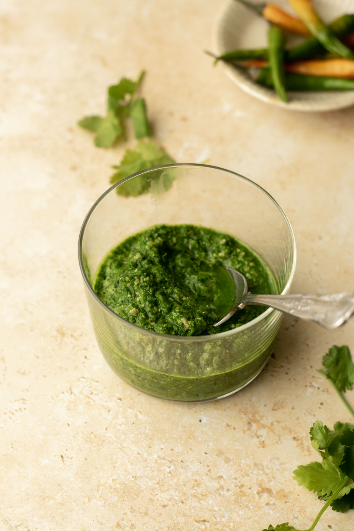 a bowl of coriander chutney and some chillies