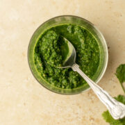a bowl of coriander chutney with a spoon in it
