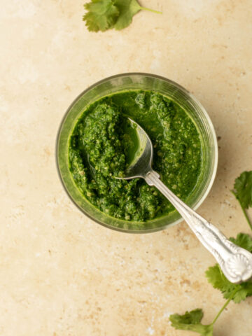 a bowl of coriander chutney with a spoon in it