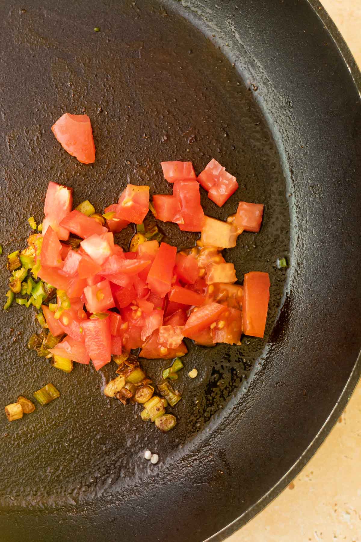 tomatoes, spring onion and spices in a frying pan