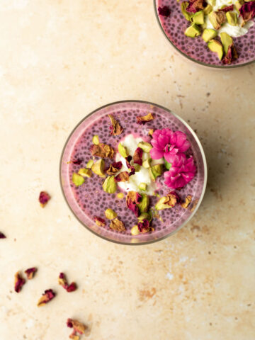 a bowl of chia seed pudding topped with rose petals, pistachios and flowers