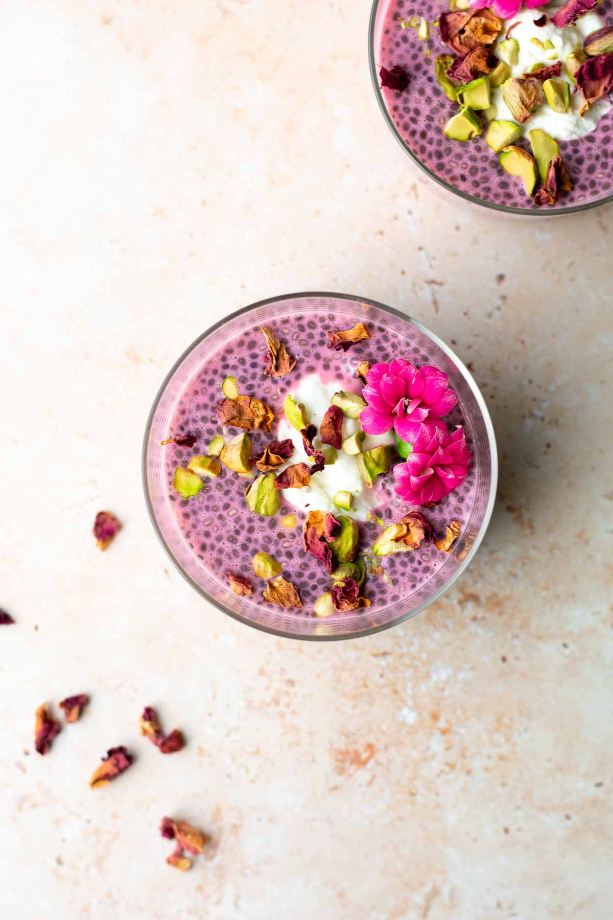 a bowl of chia seed pudding topped with rose petals, pistachios and flowers