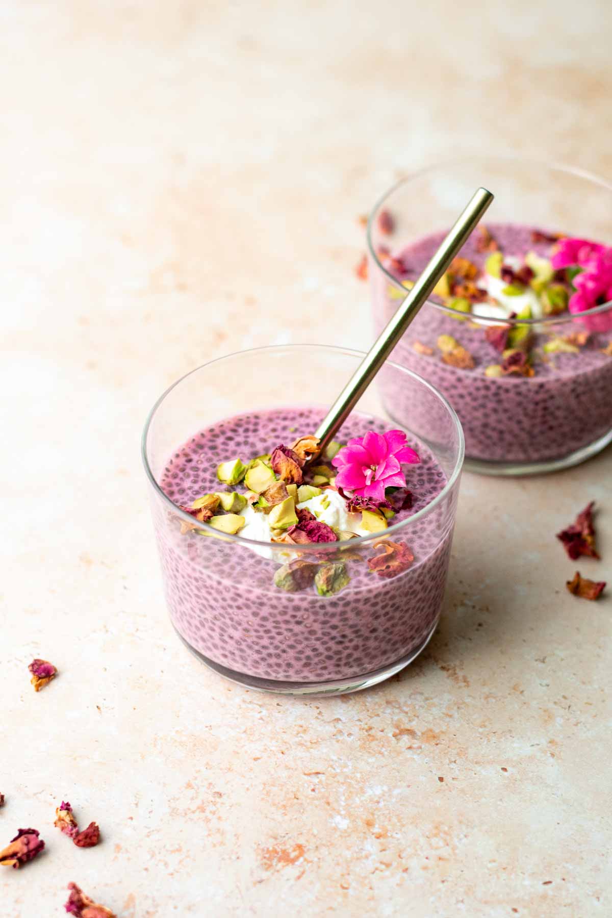 two small glasses filled with rose chia pudding and garnished with rose petals