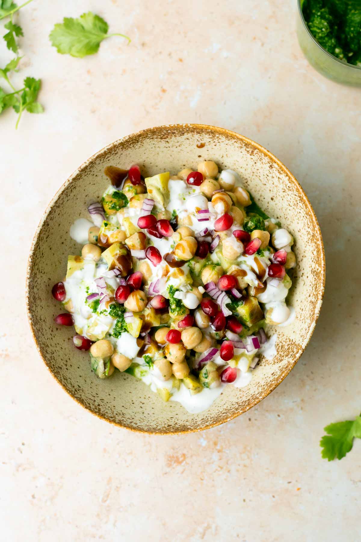 a bowl of chaat with yogurt, pomegranate and chutneys