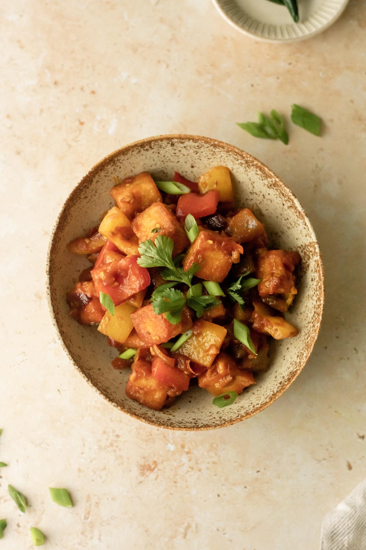 a bowl of chilli paneer garnished with onions and coriander