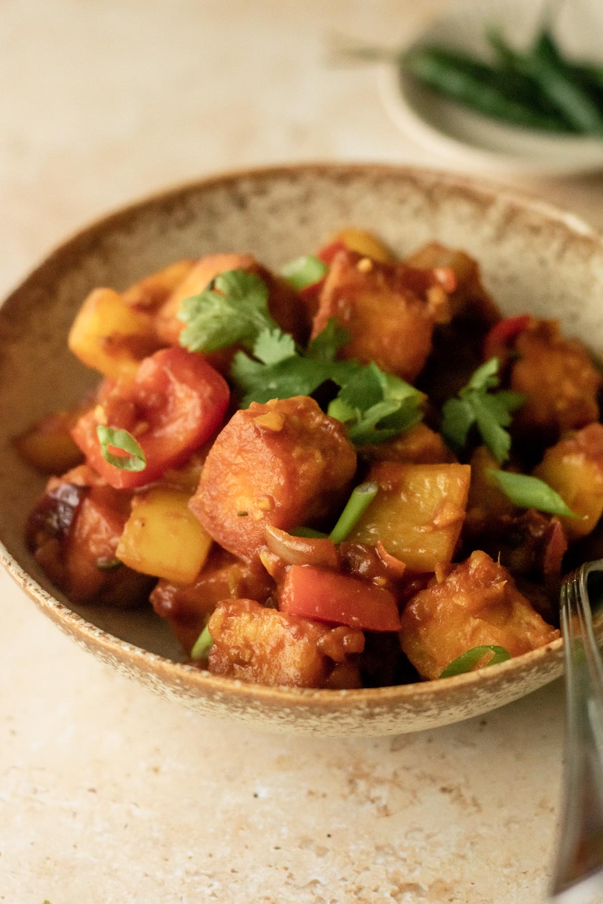a bowl of chilli paneer with a spoon